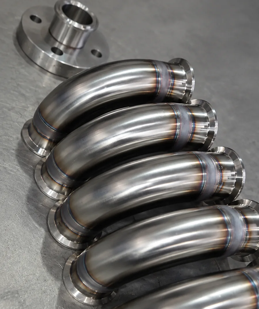 Five polished metal pipe bends stacked together.